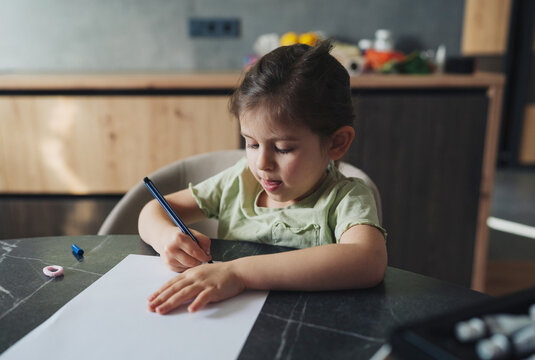 caucasian girl focused on artistic creation, child passionately engaged in drawing with art supplies