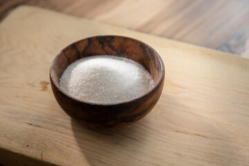 Granulated sugar filled in a wooden bowl, harmful to health theme