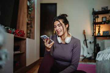 Woman smiling while recording voice message on smartphone at home