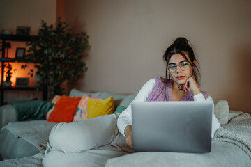 Woman relaxing on sofa using laptop at home