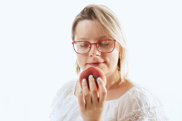 Pretty woman smells peach, fresh ripe fruit as a source of vitamin. Healthy snack, vegetarian