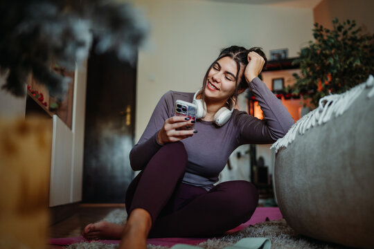Woman relaxing at home using smartphone and headphones