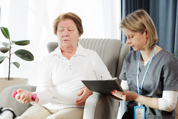 Assistant to a senior woman talking with her about her health and physiotherapy she needs