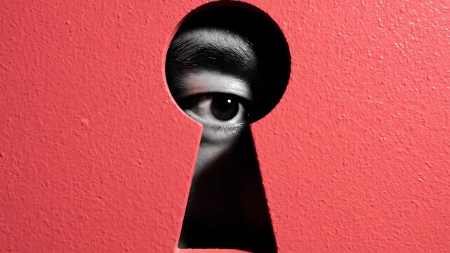 Human eye looking through keyhole in red door symbolizing curiosity spying voyeurism and invasion of privacy or secret discovery mystery concepts
