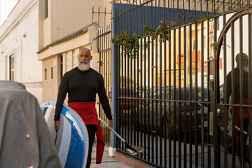 Mature man walking with paddleboard and paddle