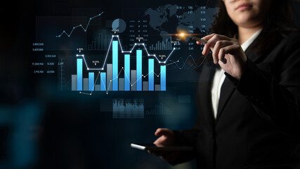 A businesswoman engages with digital financial data, highlighting trends and statistics in a modern office setting, emphasizing technology in analysis and decision-making. Scalp