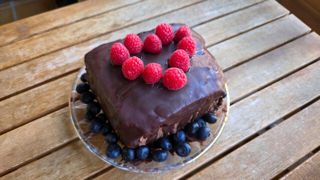 Delicious homemade chocolate cake with fresh berries on wooden table for dessert celebration. World Cake Day