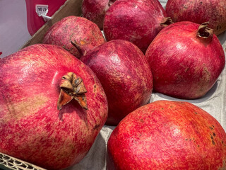 Fresh red pomegranates displayed in cardboard box at market