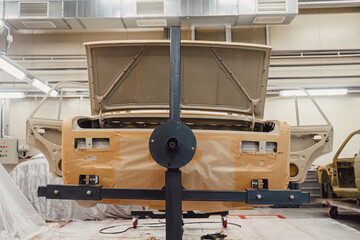 Specialist spraying anti rust sealant into the hidden chassis cavities. Protection against corrosion and internal body element sealing in a professional auto service shop