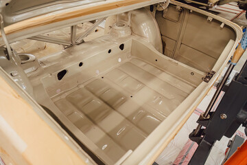 Specialist spraying anti rust sealant into the hidden chassis cavities. Protection against corrosion and internal body element sealing in a professional auto service shop