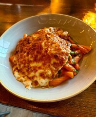 Baked pasta dish topped with melted cheese in a ceramic bowl