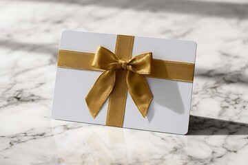 A pristine white gift card adorned with a luxurious golden ribbon and bow, resting elegantly on a polished marble surface, perfect for any special occasion.
