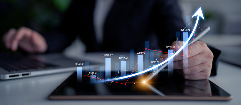 A business professional examines financial data on a tablet, highlighting an upward trend graph that represents growth and success in a corporate workspace. Scalp - Powered by Adobe