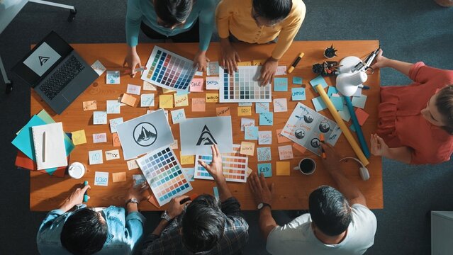 Top down view of smart designer explain and brainstorming idea for logo design and writing concept. Aerial view of business people discuss and talking while using sticky notes sharing idea. Symposium.