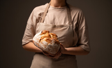 Artisan baker presenting rustic handmade bread loaf, showcasing traditional craftsmanship and natural quality