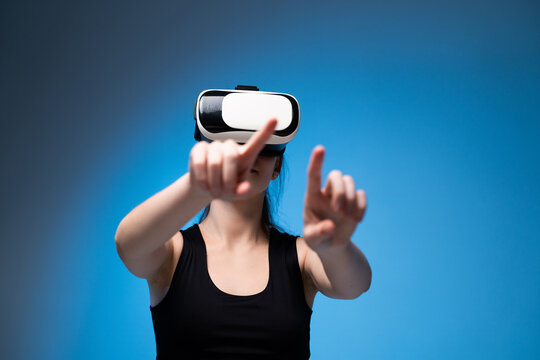 Woman interacting with virtual reality interface using VR headset in bright studio with blue background lighting