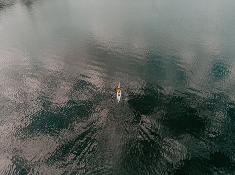 Aerial view of a lone kayaker on calm dark water