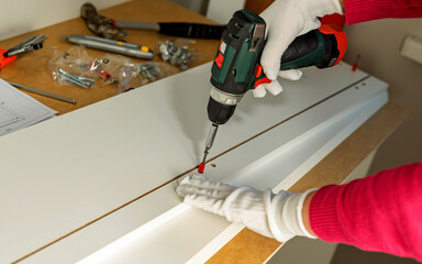The process of assembling white cabinet furniture using a screwdriver