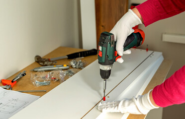 The process of assembling white cabinet furniture using a screwdriver
