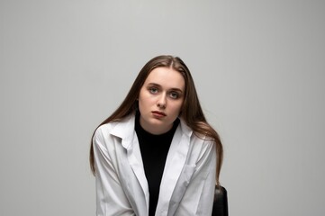Fototapeta premium Young woman staring with neutral sad expression in studio portrait on clean gray background