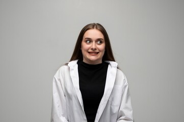 Young woman making nervous grimace with tense smile in studio portrait on gray background