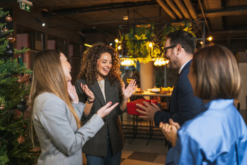 Colleagues celebrating holiday season with surprise gift giving