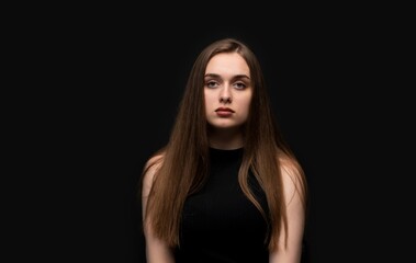 Young woman posing for neutral studio portrait on black background with natural expression and straight posture