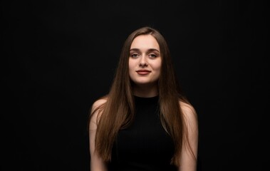Fototapeta premium Young woman on black background with calm confident expression and natural look