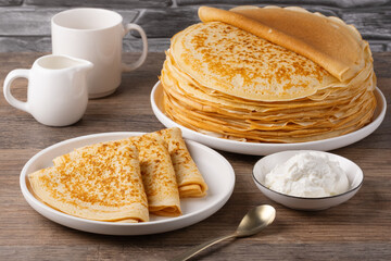 Traditional Russian pancakes with sour cream on a wooden table. Homemade russian thin pancakes blini. Russian food, russian kitchen