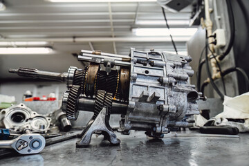 Professional car gearbox transmission repair and maintenance service in an industrial garage. Mechanical parts background for advertising or technical documentation.