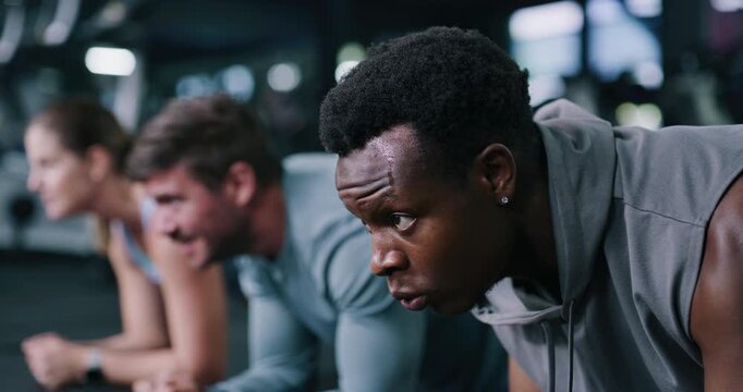 Athletes, plank and man in gym, fitness and people with personal trainer for strength and endurance. Health club, balance and group with instructor for workout, breathing and training for wellness