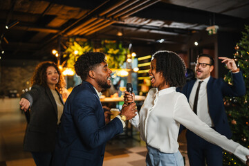 Diverse colleagues celebrating and singing karaoke at office christmas party