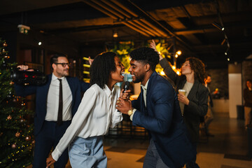 Diverse office colleagues singing karaoke at christmas party