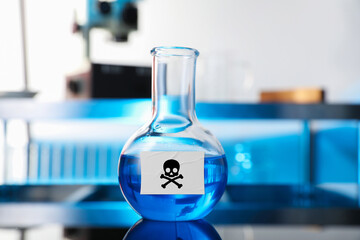 Poison in flask on table. Laboratory glassware with skull and crossbones label
