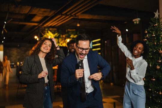 Business colleagues singing karaoke enjoying office christmas party