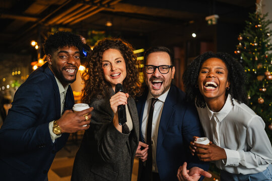 Diverse colleagues celebrating party night singing karaoke