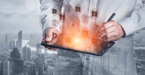 A professional male in a lab coat uses a tablet to engage with data management and cloud security, with abstract icons emerging over a modern cityscape backdrop. Gantry