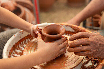 Child's Hands Learning Pottery on a Wheel with an Adult Instructor, Intergenerational Craft