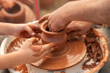 Child's Hands Learning Pottery on a Wheel with an Adult Instructor, Intergenerational Craft