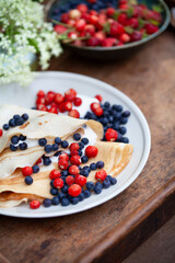Delicious homemade crepes with fresh fruit  -  blueberry and alpine strawberry. Gourmet picnic snack ina spring garden.
