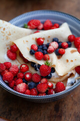 Delicious homemade crepes with fresh fruit  -  blueberry and alpine strawberry. Gourmet picnic snack ina spring garden.