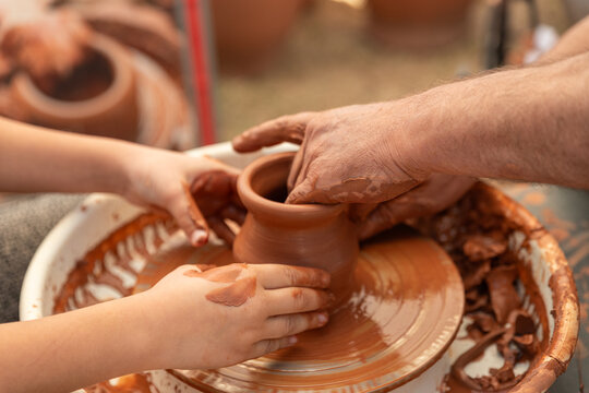 Child's Hands Learning Pottery on a Wheel with an Adult Instructor, Intergenerational Craft - Powered by Adobe
