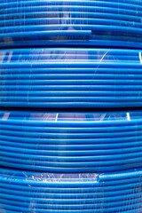 pneumatic air hose coiled and tightly wrapped in clear plastic packaging, creating a textured background pattern. Concept for industrial supply, compressed air systems, and workshop equipment for cata