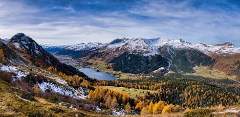 Alpine Valley Golden Larches Snow Dusted Peaks Under Expansive Blue Sky, Winding Hiking Trail Through Colorful Meadow And Rocky Ridge, Crisp Autumn. Autumn panorama in Davos with a view of the lake.