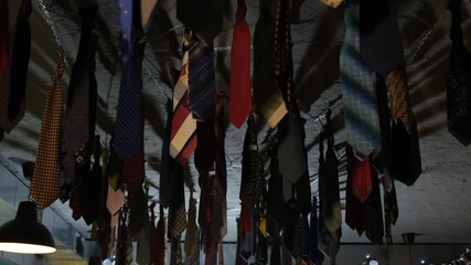 A bunch of ties hanging from the ceiling of a room