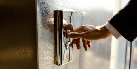 Close-up. A human finger presses an elevator button. A man's hand indoors. A red button. Concept of...