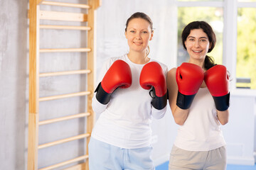 Focused woman practicing boxing punches in sparring during group self defence course in gym