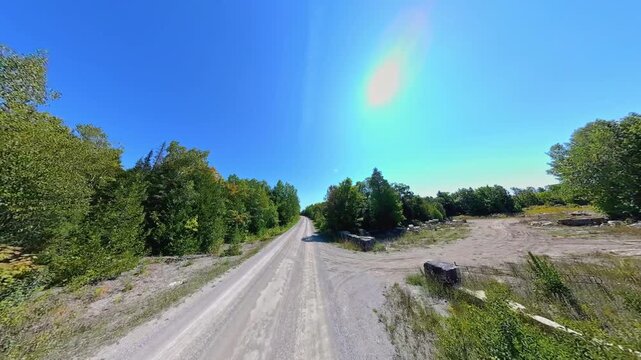 Forward view country road front driving plate POV, high side walls of lush trees. Driving car in country road at early fall in Manitoulin Island. Gibraltar Road near Lake Manitou, Ontario, Canada.