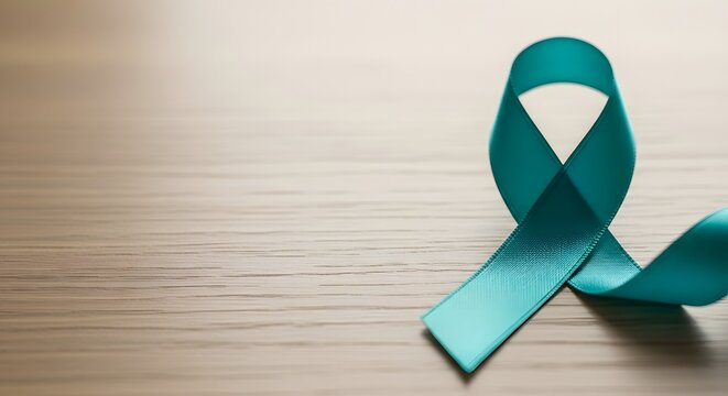 Teal awareness ribbon displayed on a light wooden table with soft focus for cervical cancer awareness concept and women's health with copy space