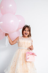Caucasian young girl in party dress holding pink balloons and gift
